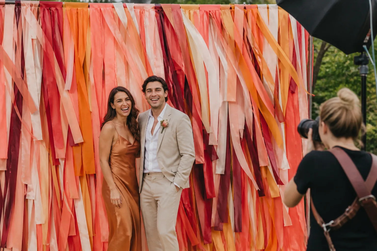 Wedding guests posing in front of a colorful matte ribbon photo booth installation