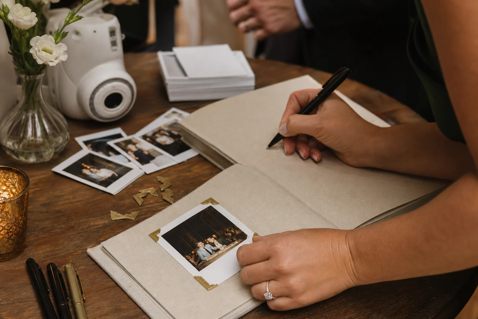 Wedding guest attaching an instant photo to a linen guest book and preparing to write a note