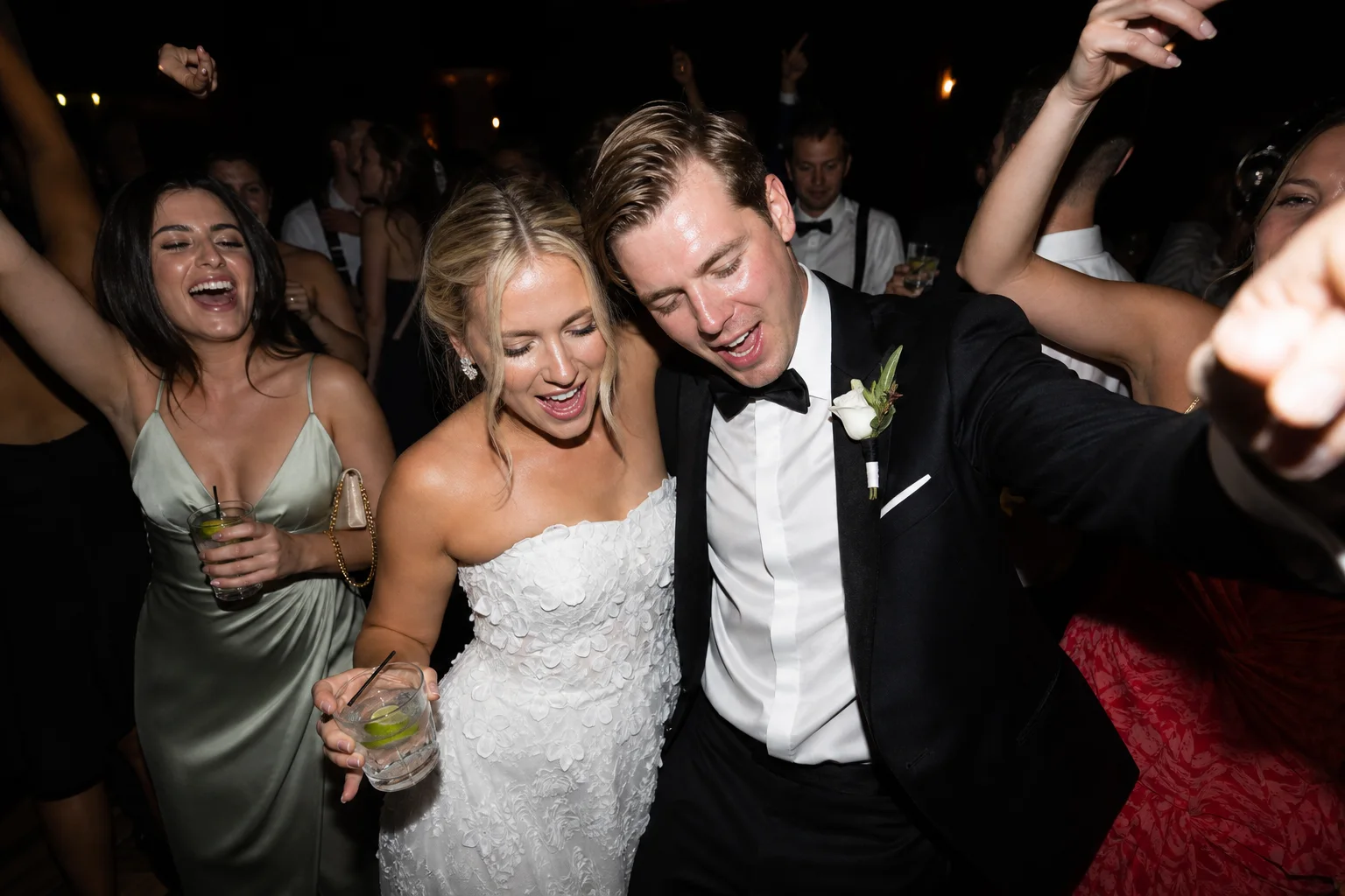 Energetic direct-flash wedding reception photograph on a crowded dance floor