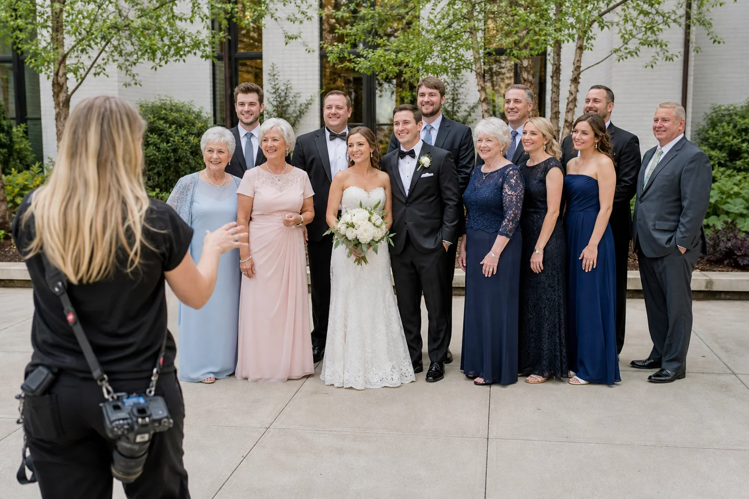 Wedding photographer organizing a family group portrait in even outdoor light